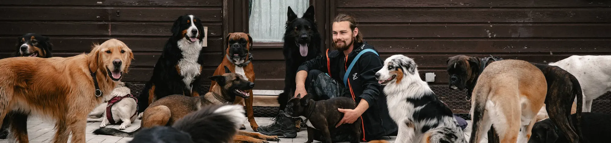 Lucas Becker mit seinem Hunderudel vor einer Holzhütte